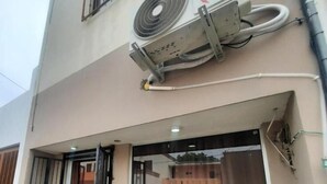 A building with a large window, a door, and an air conditioning unit mounted on the exterior wall.