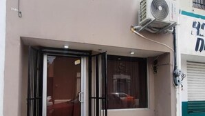 A building with a glass door entrance, an air conditioning unit mounted on the wall, and a visible window.