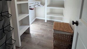 A walk-in closet with open shelves, a hanging rack, and a wicker basket. - Downtown Retreat (Durango)