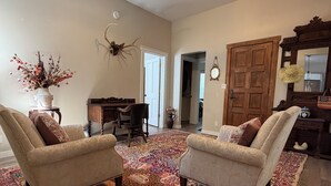 A living room with two armchairs, a patterned rug, a wooden door, and a mirror. - Downtown Retreat (Durango)