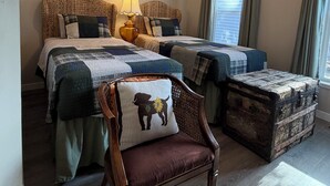 A bedroom with two beds, a wooden chair, a lamp, and a window with curtains. - Downtown Retreat (Durango)