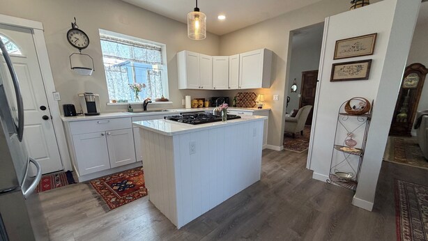 A modern kitchen with white cabinetry, a central island, and a hanging light fixture. - Downtown Retreat (Durango)