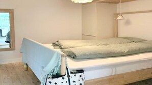 Ein schlichter Schlafzimmer mit einem Bett, einer Pendelleuchte und einem Fenster.