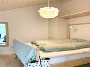 Ein schlichter Schlafzimmer mit einem Bett, einer Pendelleuchte und einem Fenster.