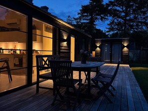 Ein modernes Haus mit Terrasse, Sitzgelegenheiten im Freien und einer gut beleuchteten Küche.