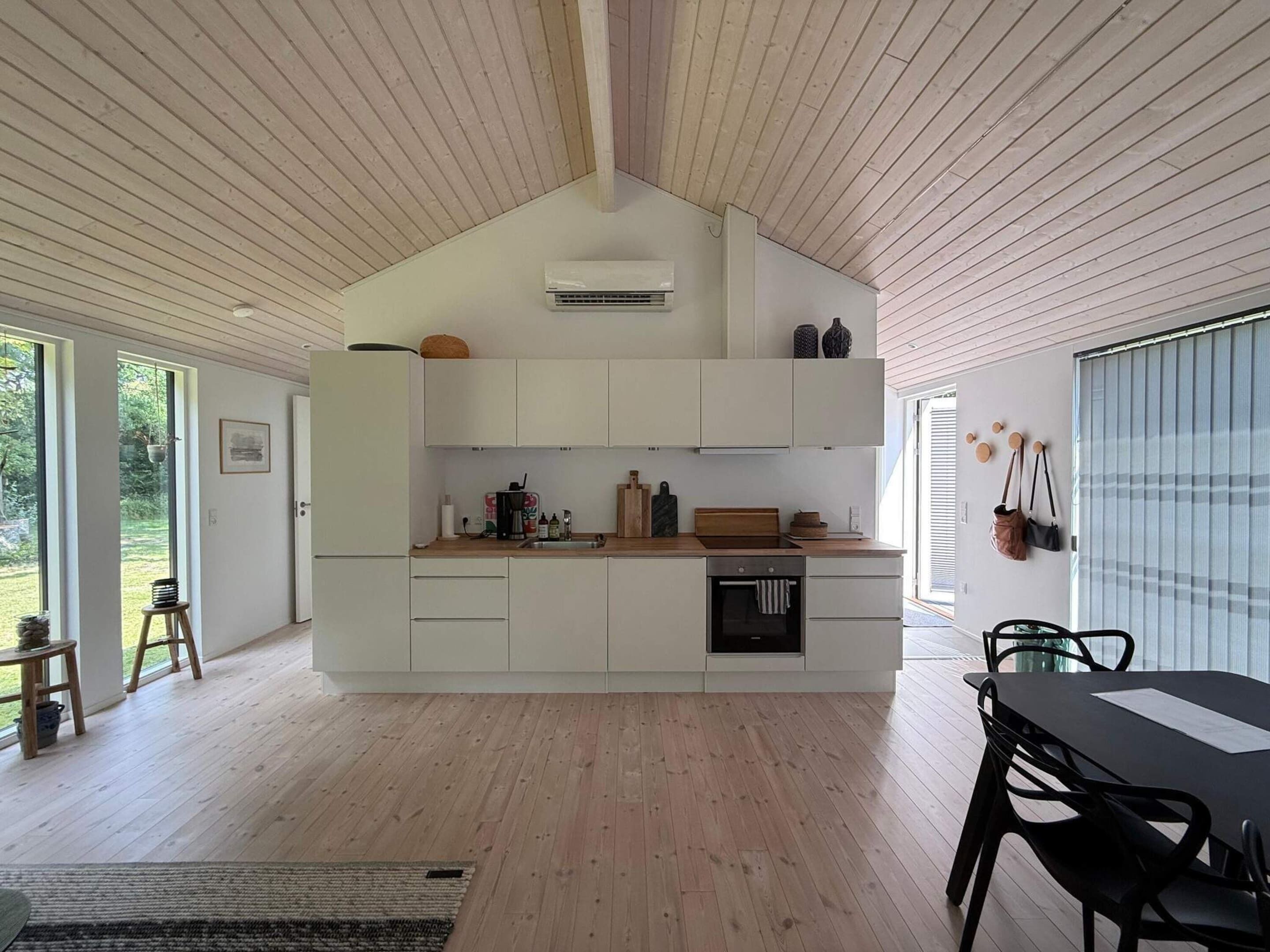 A modern kitchen with white cabinetry, a wooden countertop, and a built-in oven.