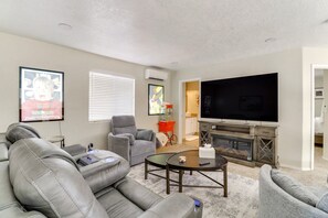 A living room with a fireplace, a large flat-screen TV, a grey sofa, and a coffee table. - Heated Pool! Hot Tub! Volleyball court! 3-bedroom, 3-Bathroom Fabolous Home! (Albuquerque)