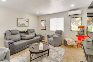 A living room with a grey sofa, a grey armchair, a small round table, and a red popcorn machine. - Heated Pool! Hot Tub! Volleyball court! 3-bedroom, 3-Bathroom Fabolous Home! (Albuquerque)