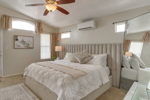 Ein Schlafzimmer mit einem Bett, Deckenventilator, Klimaanlage und einem Nachttisch mit Lampe.