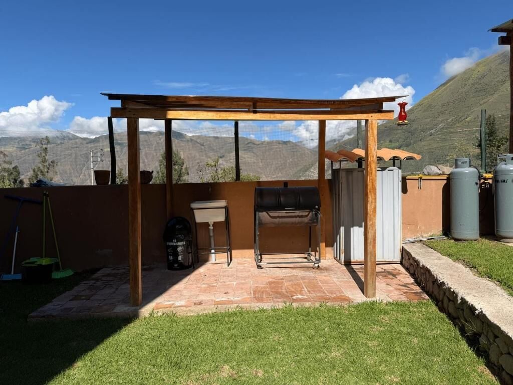 A patio with a grill, a table, and a pergola.