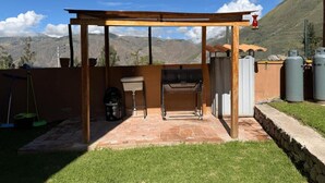 A patio with a grill, a table, and a pergola. - Auka Boutique (Urubamba)