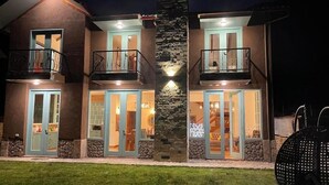 A two-story house with a stone pillar, balconies, and a well-lit entrance. - Auka Boutique (Urubamba)