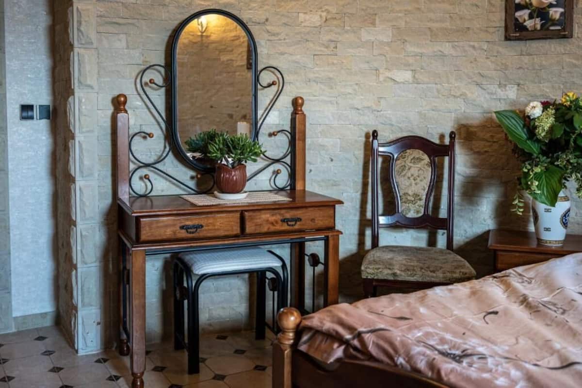 A room with a wooden dresser, a mirror, a chair, and a bed.