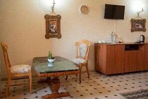 A dining area with a wooden table and chairs, a cabinet, a television, and wall-mounted artwork. - Castel Unghern (Ivancea)