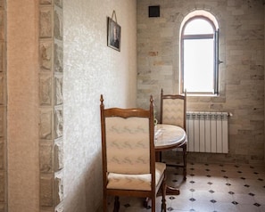 A room with stone walls, a wooden chair, a table, and a window with a view.