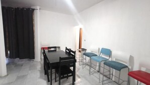 A room with a dining table and chairs, a small side table, and a lamp. - Casa Paisa Planta Alta (Linares)