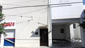 A building with a garage entrance, a sign with 'GARZA' on it, and a door leading to an interior space. - Casa Paisa Planta Alta (Linares)