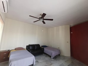 A bedroom with a bed, a chair, a small table, and a ceiling fan. - Casa Paisa Planta Alta (Linares)