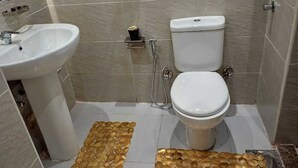 Et badeværelse med vask, toilet og bruser.