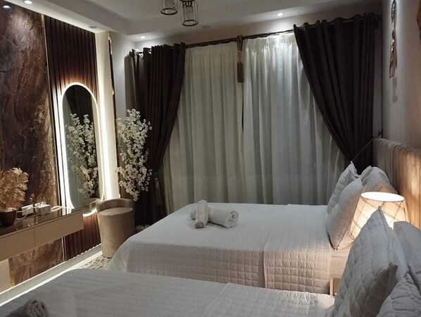 Ein Schlafzimmer mit einem großen Bett, einem Nachttisch, einem Spiegel und einem Fenster mit Vorhängen.