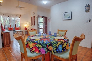 A dining area with a round table, chairs, and a colorful tablecloth. -  Charming Casita Beach and Pool Access 2 king beds (Q.R.)