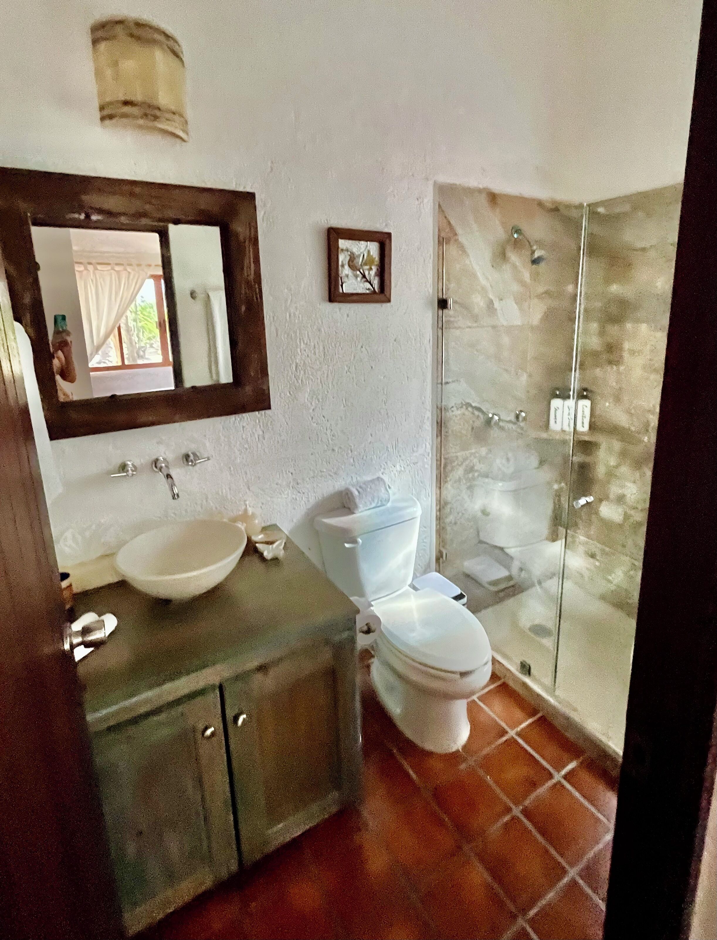 Een badkamer met een wastafel, toilet en een douchecabine van glas.