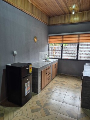 Eine Küche mit Einbaukühlschrank, Spüle, Holzschränken und einem Fenster mit Jalousien.