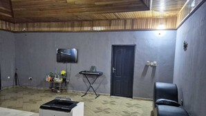 A room with a tiled floor, a printer, a keyboard, a TV, and a door. - Lux, Spacious, apt, close 2 the beach and Airport. (Greater Accra Region)