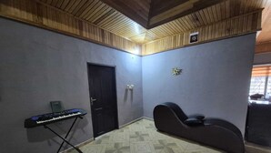A room with a piano, a black chair, a door, and a patterned floor. - Lux, Spacious, apt, close 2 the beach and Airport. (Greater Accra Region)