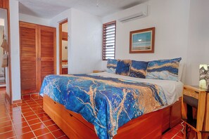Une chambre à coucher avec un lit, une armoire en bois et un tableau accroché au mur.