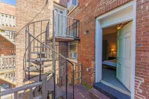 Un edificio de ladrillo con una escalera de metal en el exterior que lleva a una puerta, un pequeño balcón y una ventana.