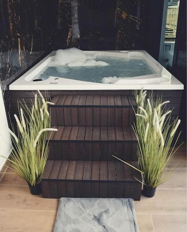 A hot tub with steps leading up to it, flanked by potted plants.. Hotel Montana