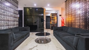 A modern living room with two dark sofas, a glass coffee table, and patterned walls. - Hotel Montana (Bello)