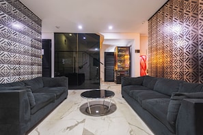 A modern living room with two dark sofas, a glass coffee table, and patterned walls. - Hotel Montana (Bello)