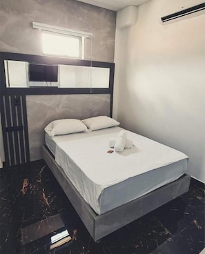 A room with a bed, a window, a wall-mounted air conditioning unit, and a marble floor. - Hotel Montana (Bello)