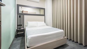 A hotel room with a bed, bedside table, air conditioning unit, and curtains. - Hotel Montana (Bello)