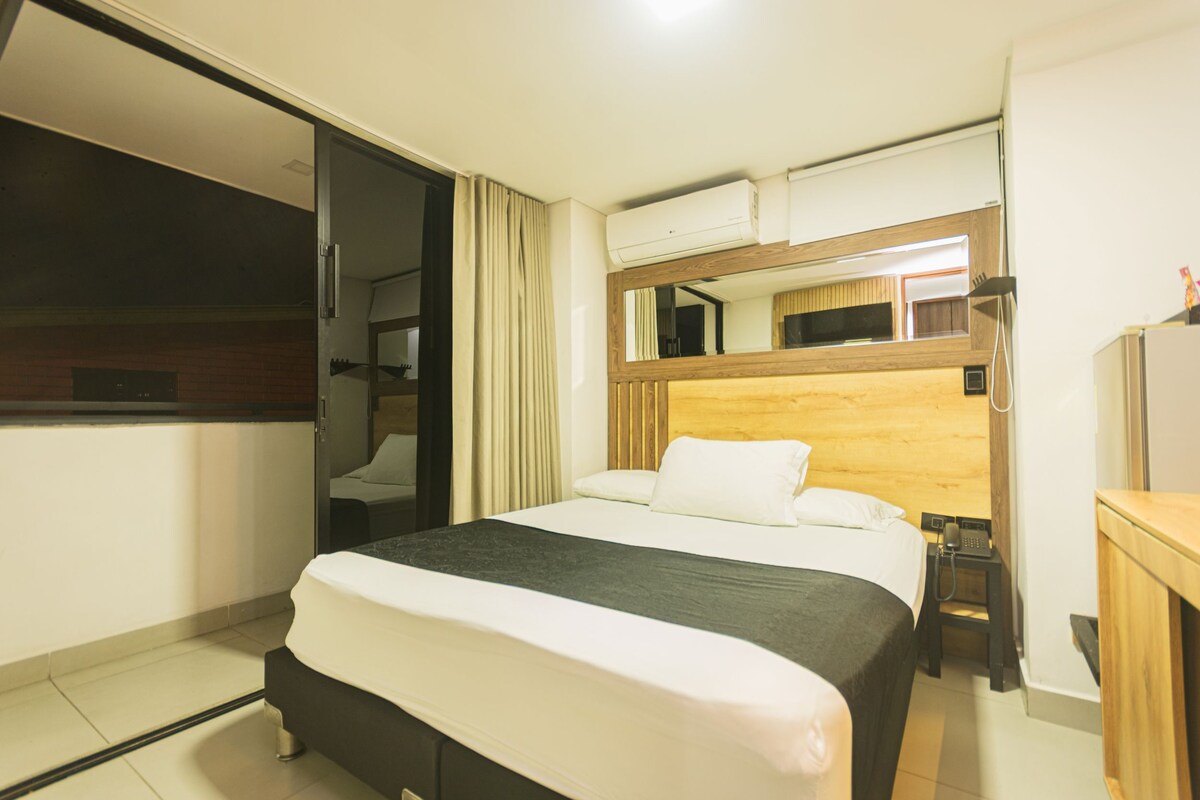 Une chambre d’hôtel équipée d’un lit, d’un bureau, d’un miroir et d’une armoire intégrée.