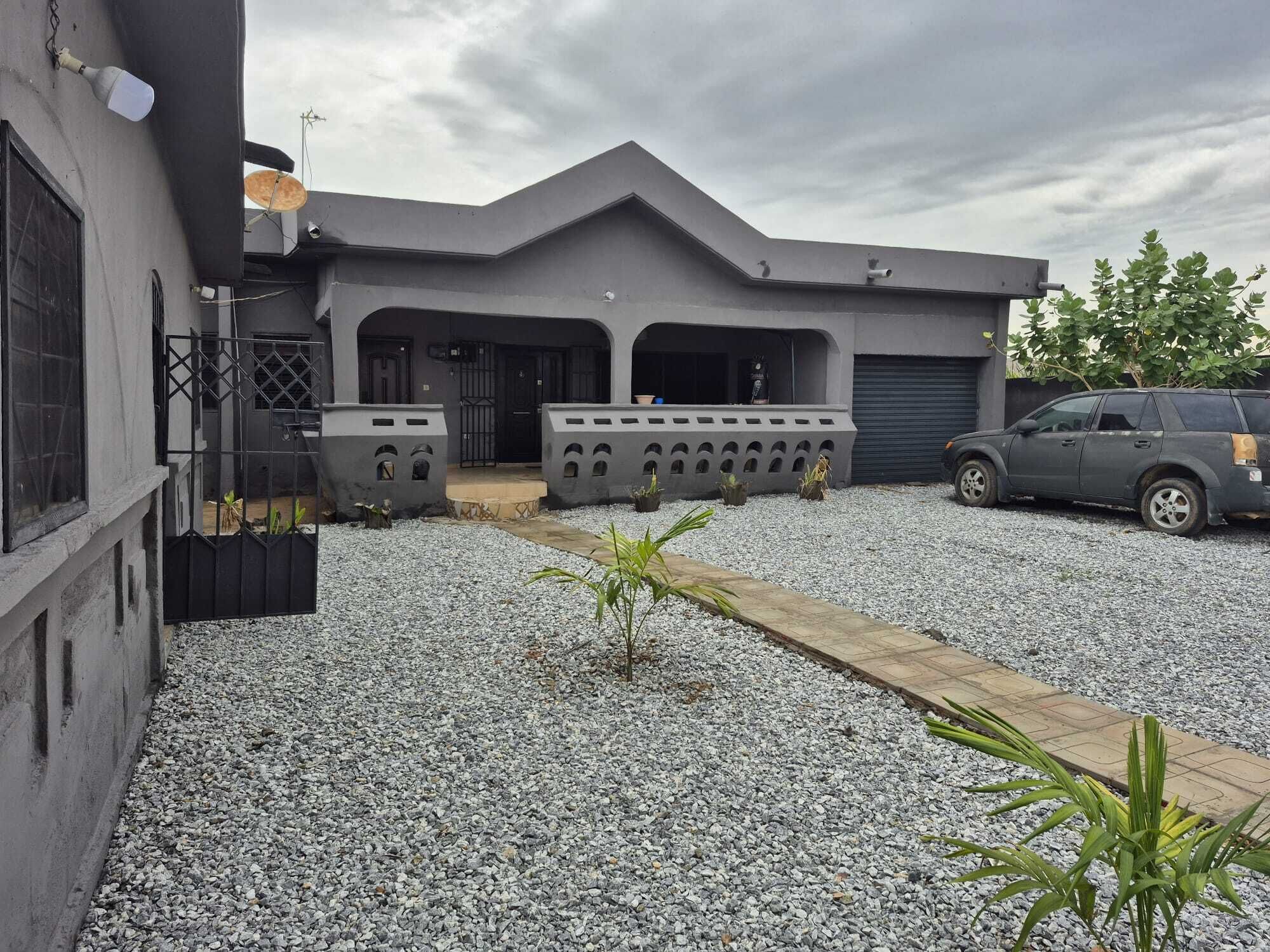 A modern building with a grey facade, a covered entrance, and a gravel driveway.