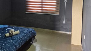 A room with a bed, a window with blinds, an air conditioning unit, and a door. - A beautiful relaxation, 10 mins to beach and 30 mins from the airport (Greater Accra Region)