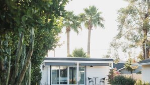 A modern house with a patio, a lawn, and tall trees in the background. - Studio Style Single Room Cottage...Luca's Place (Phoenix)