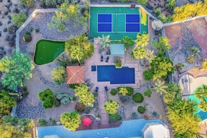 Ein Luftbild eines Anwesens mit Tennisplatz, Schwimmbad und angelegtem Garten.