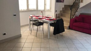 Un comedor con una mesa lista para cuatro personas, un sofá rojo y una escalera.