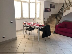 Ein Essbereich mit Tisch für vier Personen, einem roten Sofa und einer Treppe.