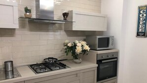 Una cocina con estufa a gas, horno, microondas y un jarrón decorativo con flores.