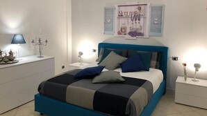 Un dormitorio con cama, mesitas de noche, lámpara y un adorno en la pared.