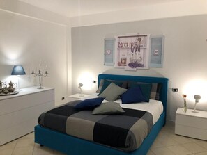 Ein Schlafzimmer mit Bett, Nachttischen, einer Lampe und einer Wanddekoration.