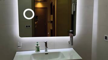 Un baño con un espejo grande, un lavamanos y dos cajones.