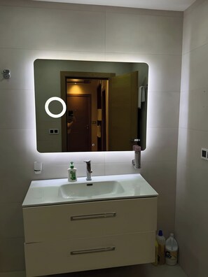 Ein Badezimmer mit einem großen Spiegel, einem Waschbecken und zwei Schubladen.