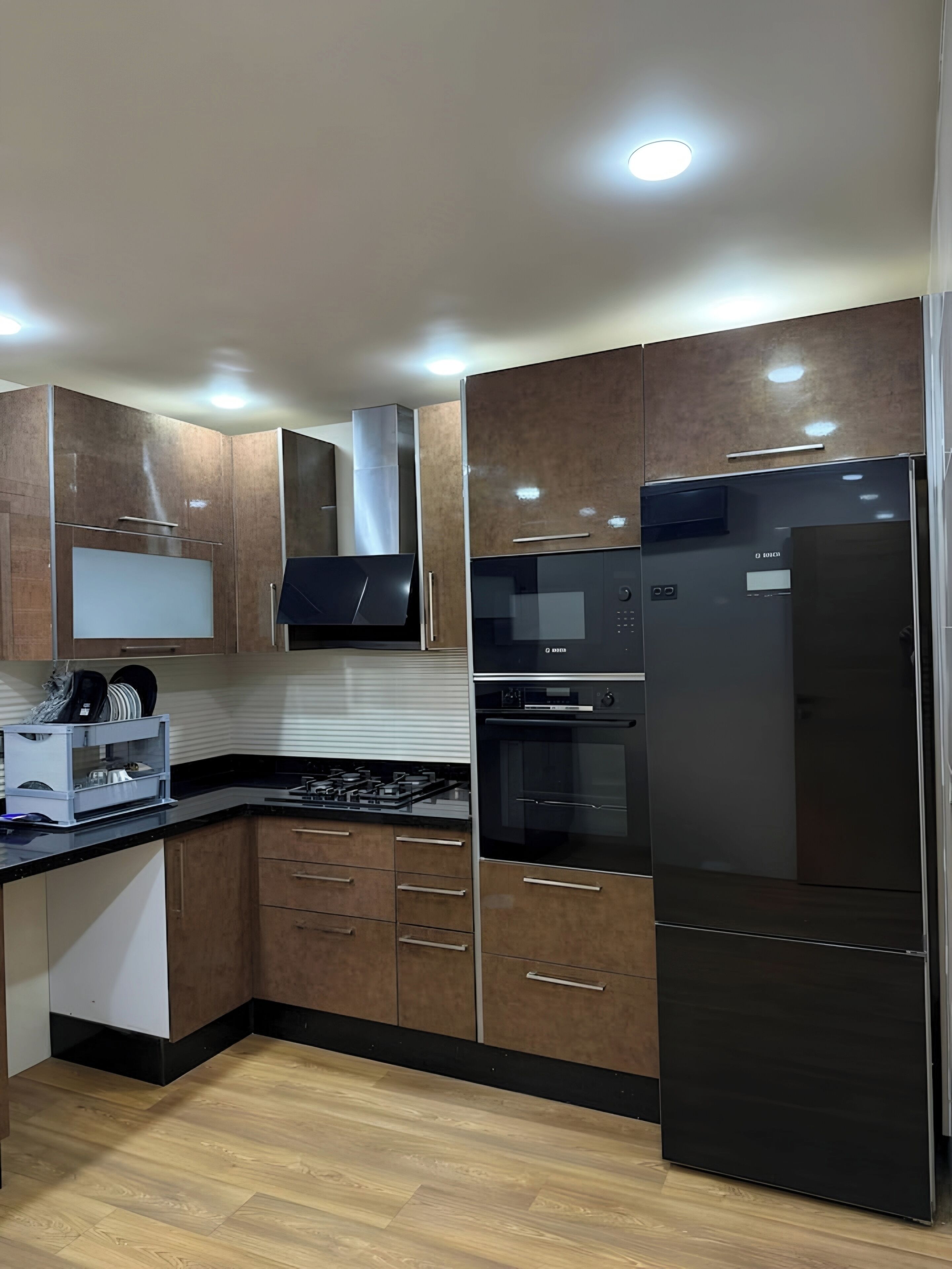 Una cocina moderna con armarios de madera, electrodomésticos de acero inoxidable y un refrigerador negro.