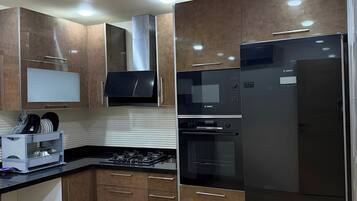 Una cocina moderna con armarios de madera, electrodomésticos de acero inoxidable y un refrigerador negro.